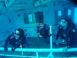 Three scuba divers looking up on the Vandenberg wreck in Key West